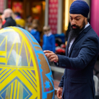 A man touching a large egg sculpture part of the Pysanka Egg display in Liverpool One high street.