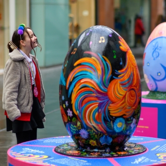 A child admiring a large egg sculpture part of the Pysanka Egg display in Liverpool One high street.