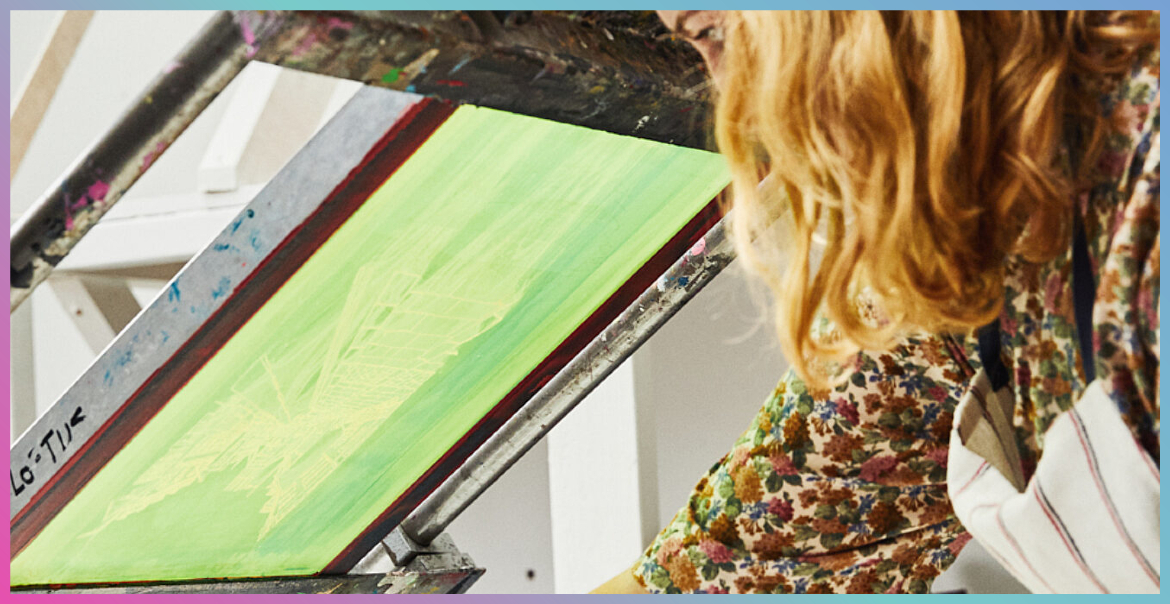 A woman screen printing a green image.