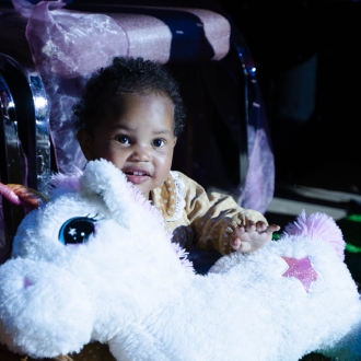 A toddler holding a unicorn plush teddy.