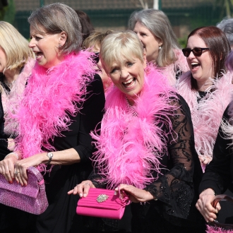 A choir of women wearing pink feather boa's.