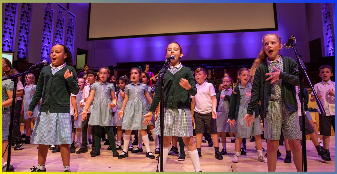 A primary school choir singing on stage.