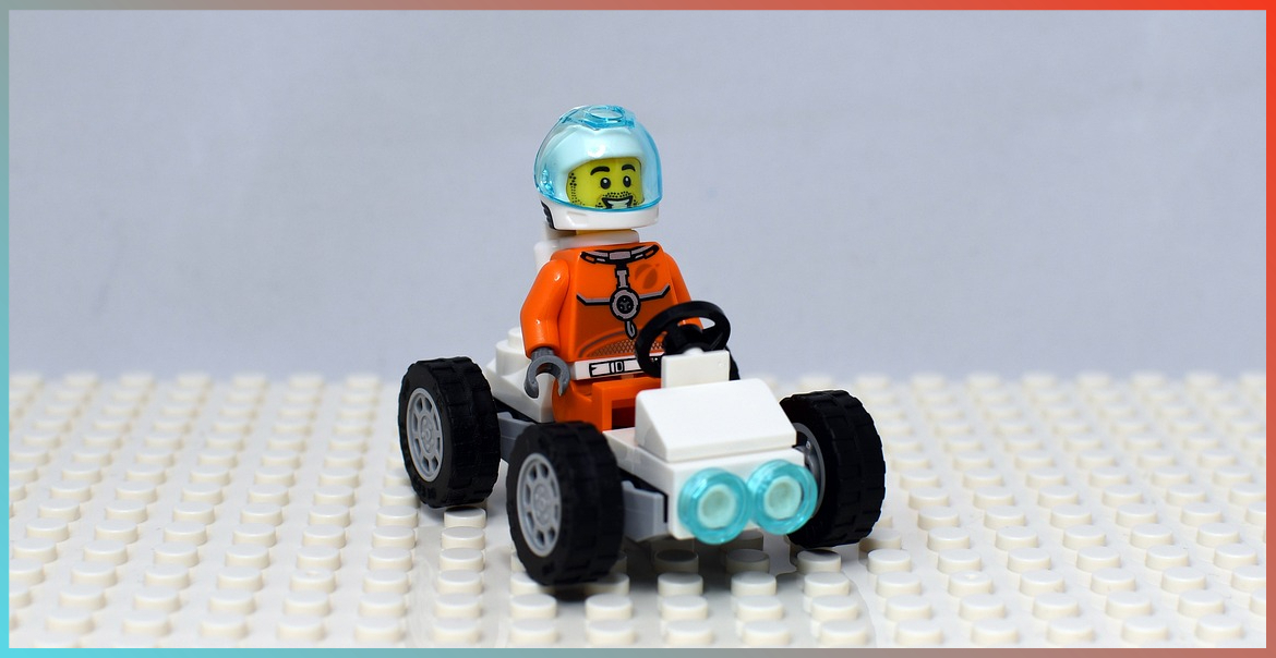 A Lego figure driving a Lego car.