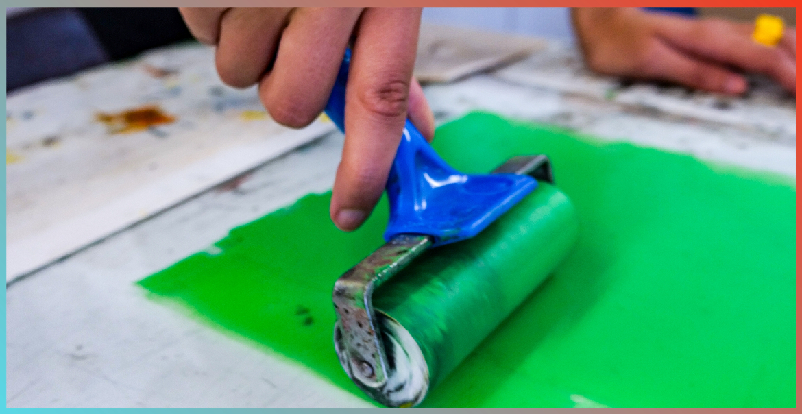 A close up image of somebody rolling green paint with a mini roller brush.