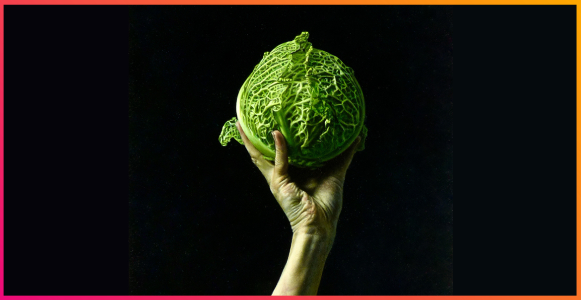 In a dark room, a hand holds up a cabbage.