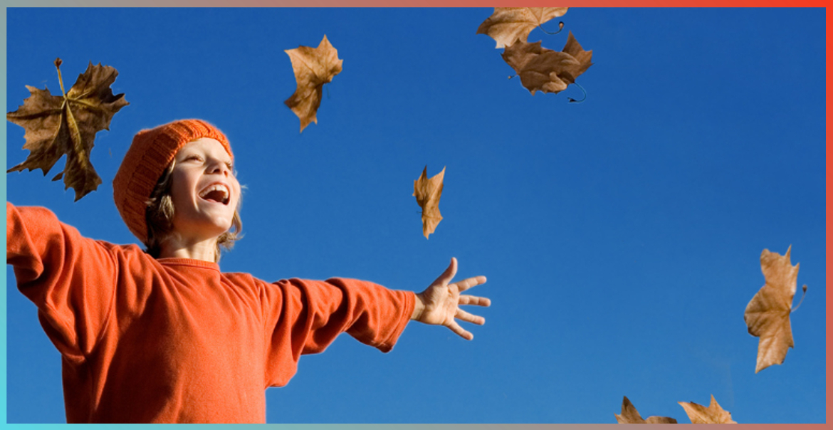 A child throwing up autumn leaves in the air.