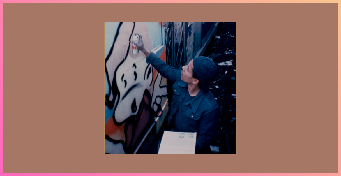 image of a man with a baseball cap on and holding paint spray whilst creating graffiti art