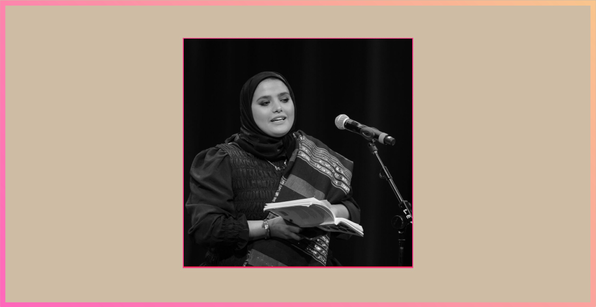 Image of Amina Atiq reading a book on stage with a microphone in front of her