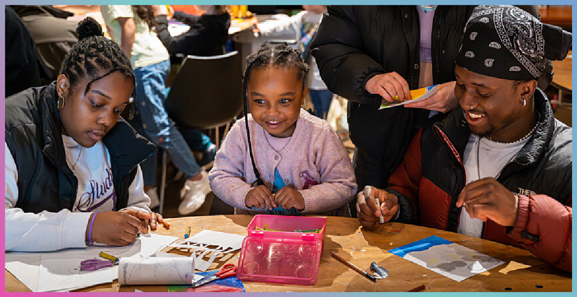 A family taking part in an art activty at a craft table.