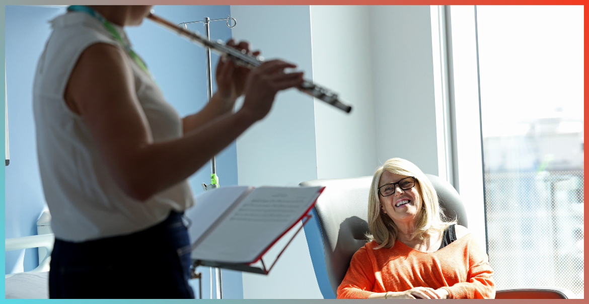 A woman admiring a musician playing the flute in a hospital setting.