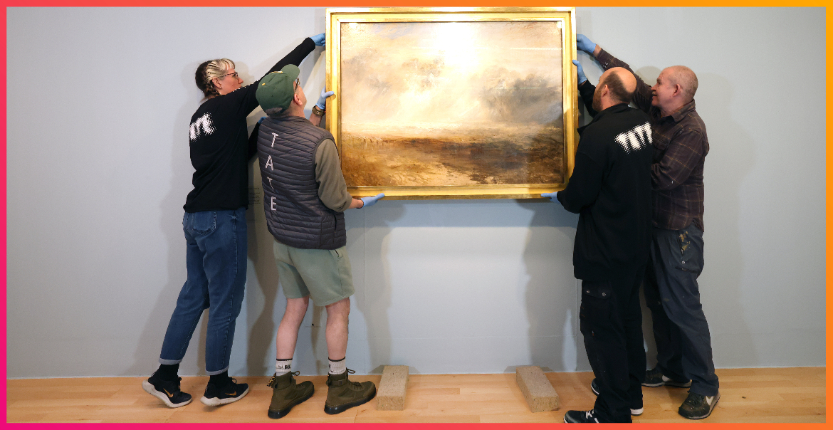 Four people carefully taking a framed painting off a wall.
