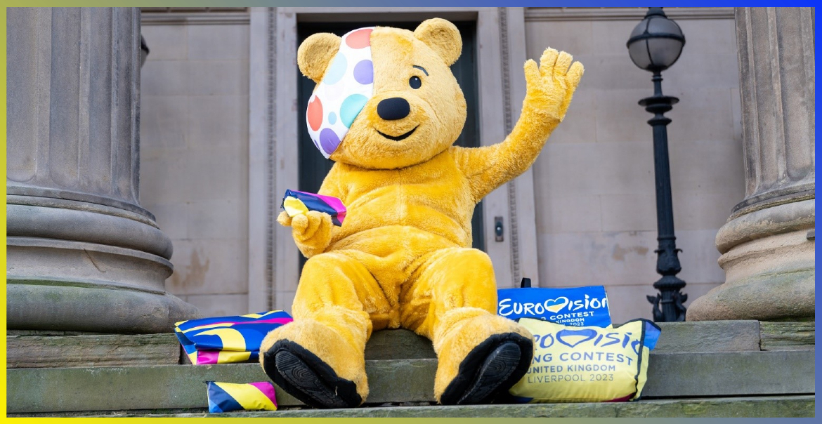 Pudsey sititng outside St George's Hall with Eurovision 2023 branded merchandise.