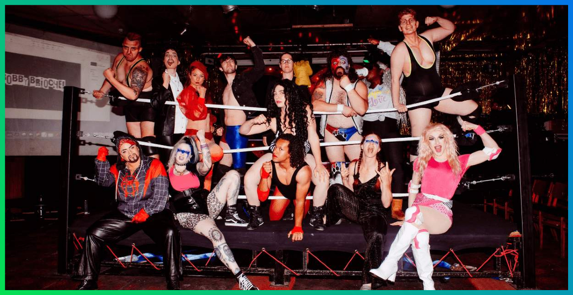 A large group of performers gathered around a wrestling ring.