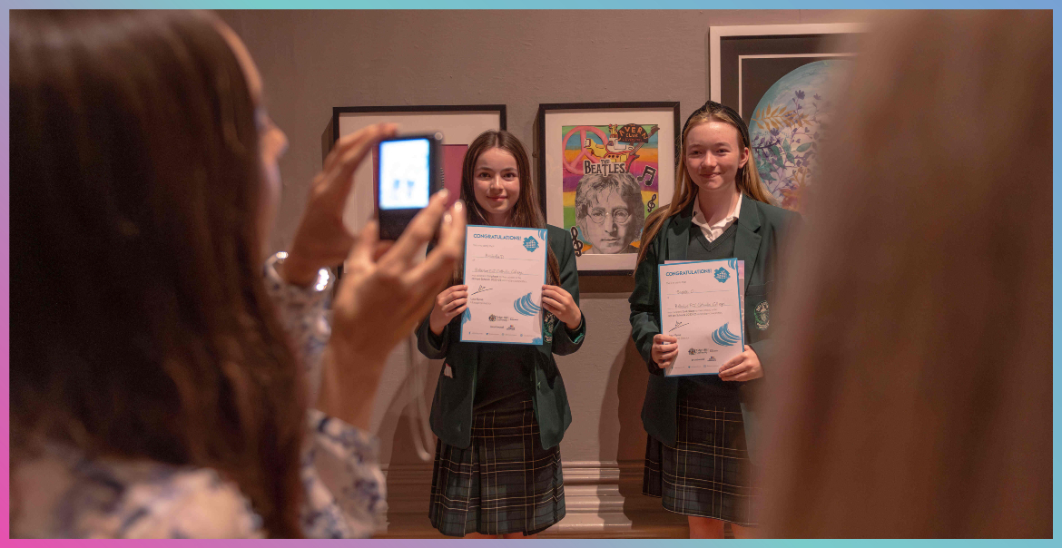 Two school pupils holdin up a certificate posing for a photo.
