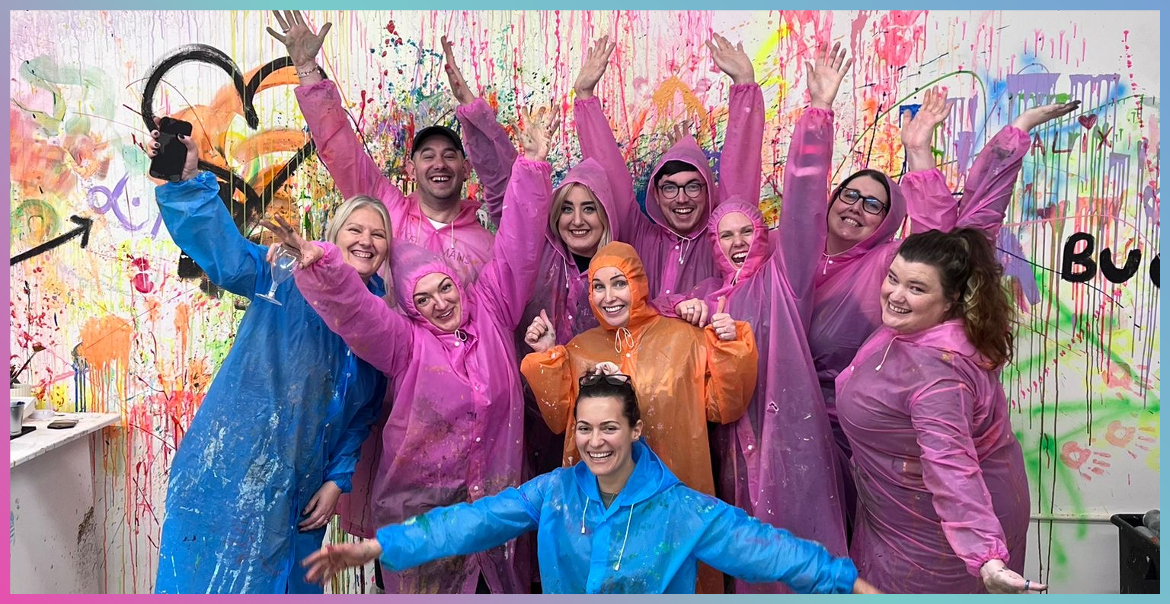 A group of people wearing ponchos with paint splattered against the wall behind them.