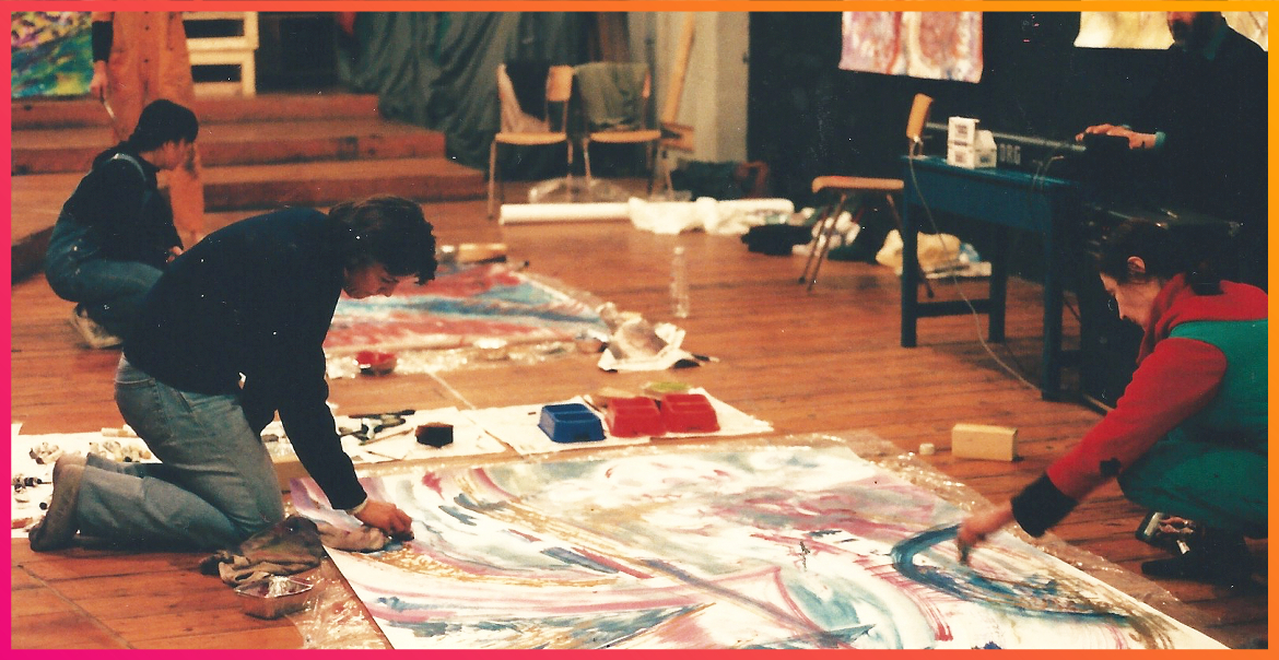 A woman painitng on the floor with art materials.