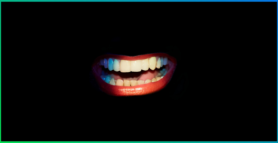 A mouth with red lips and white teeth surrounded by black.