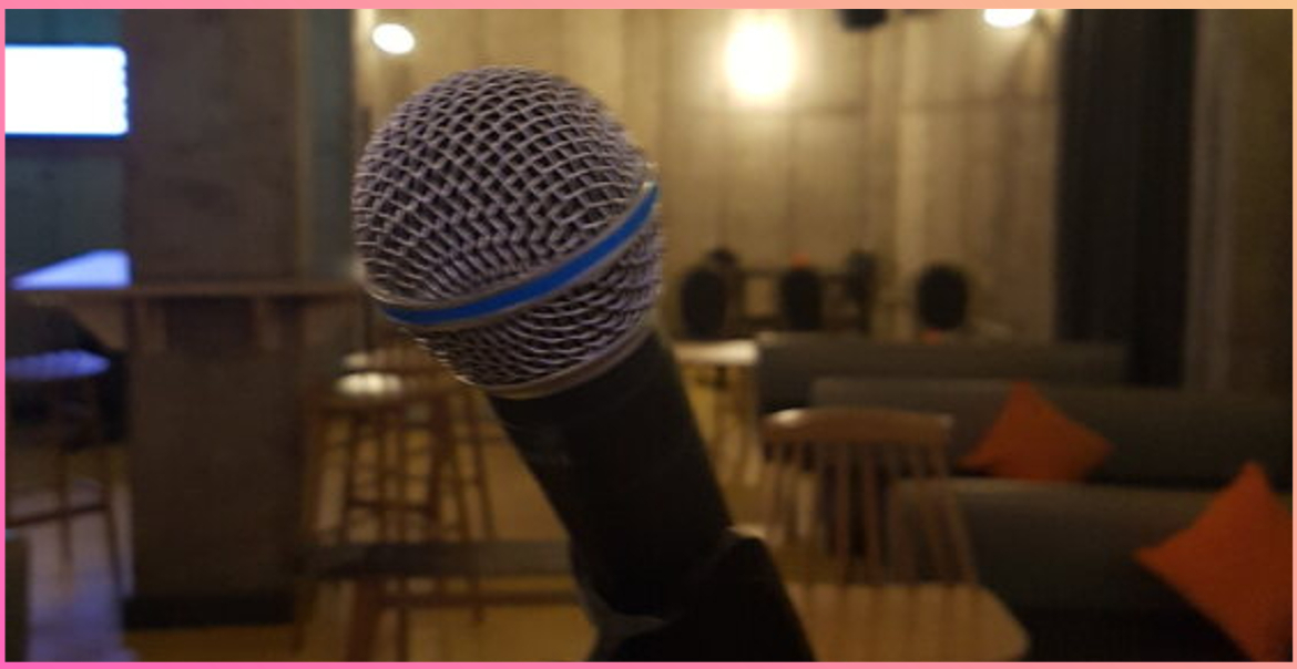 A close up image of a microphone in front of an empty venue.