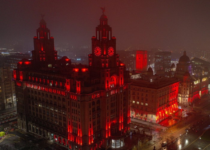 The three graces on Liverpool's waterfront lit up in red in honour of Service of Remembrance