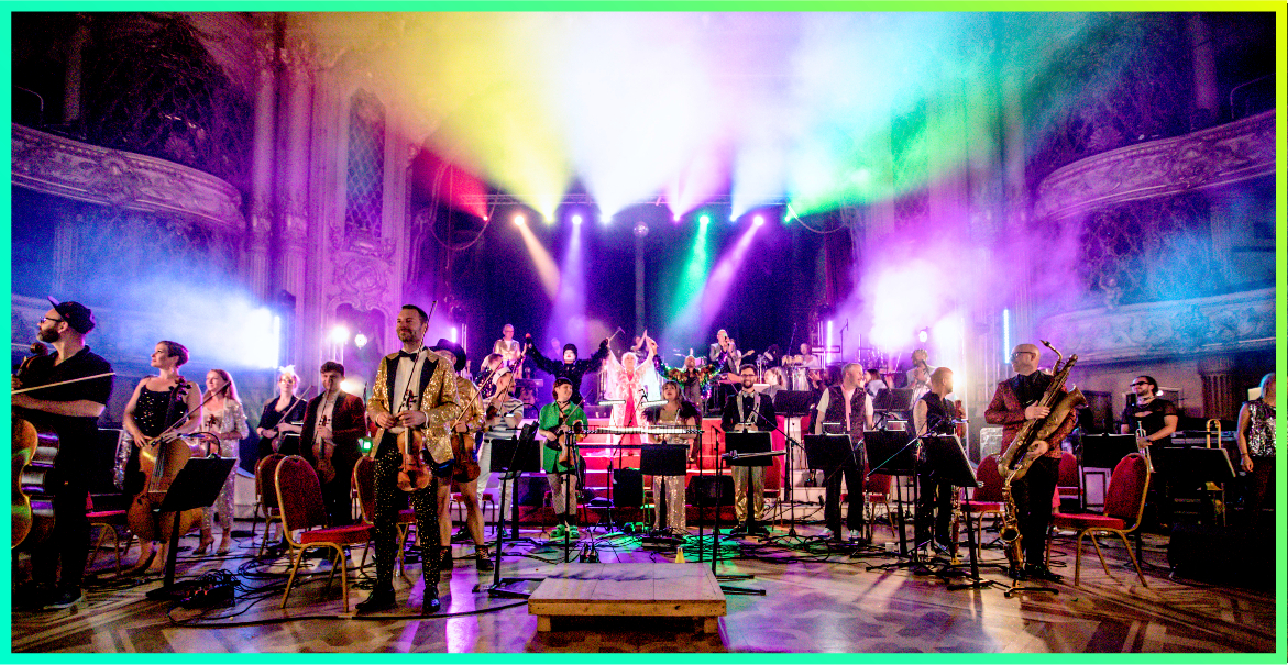 a group of musicians performing live music accompanied by a rainbow of lights