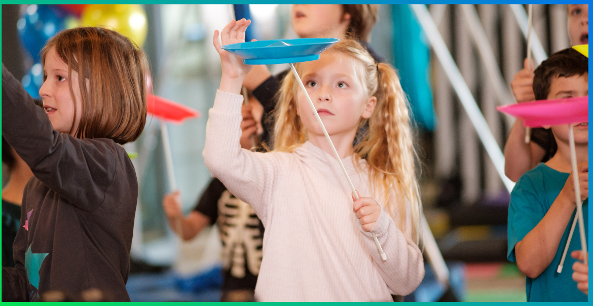 A children's circus workshop with a focus on a young girl spinning a plate.