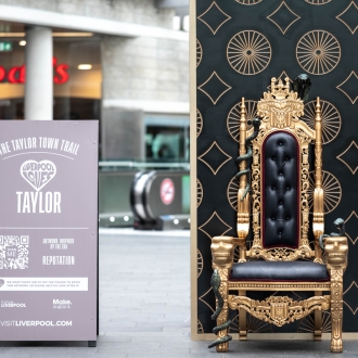 Aa gold throne with snakes curling around the arms in the middle of a covered shopping centre.