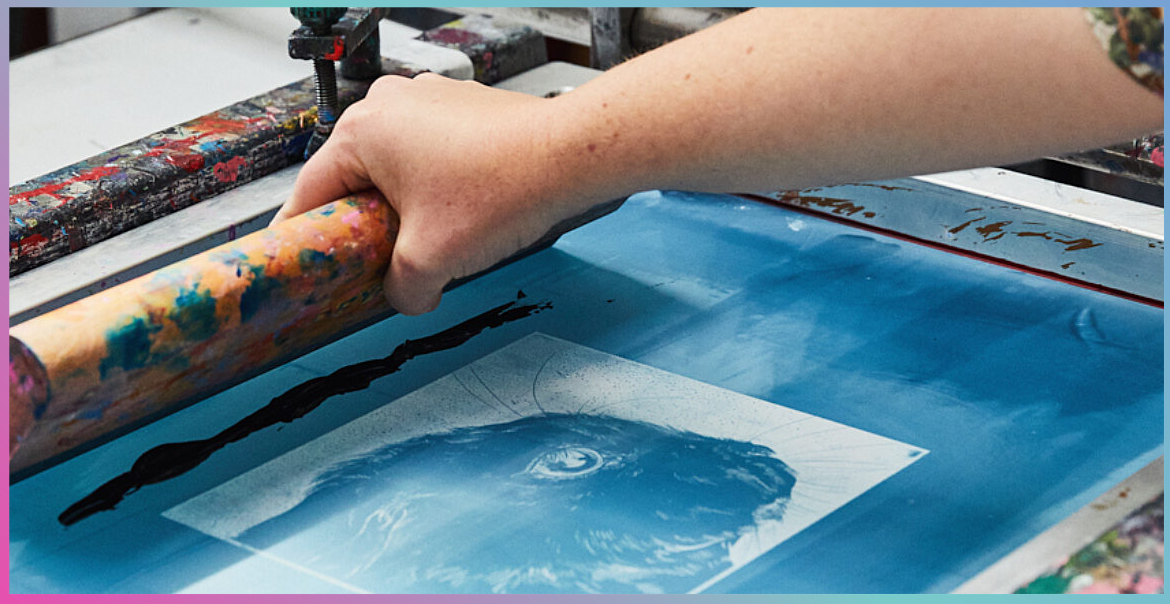 A close up image of a person screen printing.