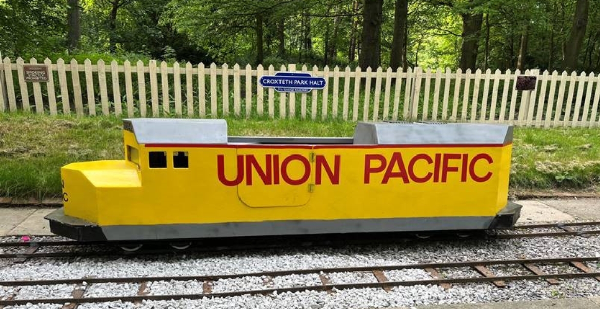 Yellow minature train carriage in Croxteth Park with red text "UNION PACIFIC" painted on the outside.