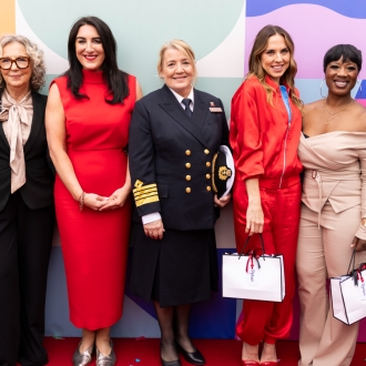 A line-up of women pose for a photo in front of a colourful backdrop at the naming ceremony of Queen Anne.