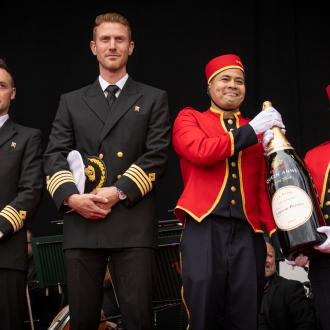 A line-up of crew from a cruise ship hold a 12 litre bottle of champagne.