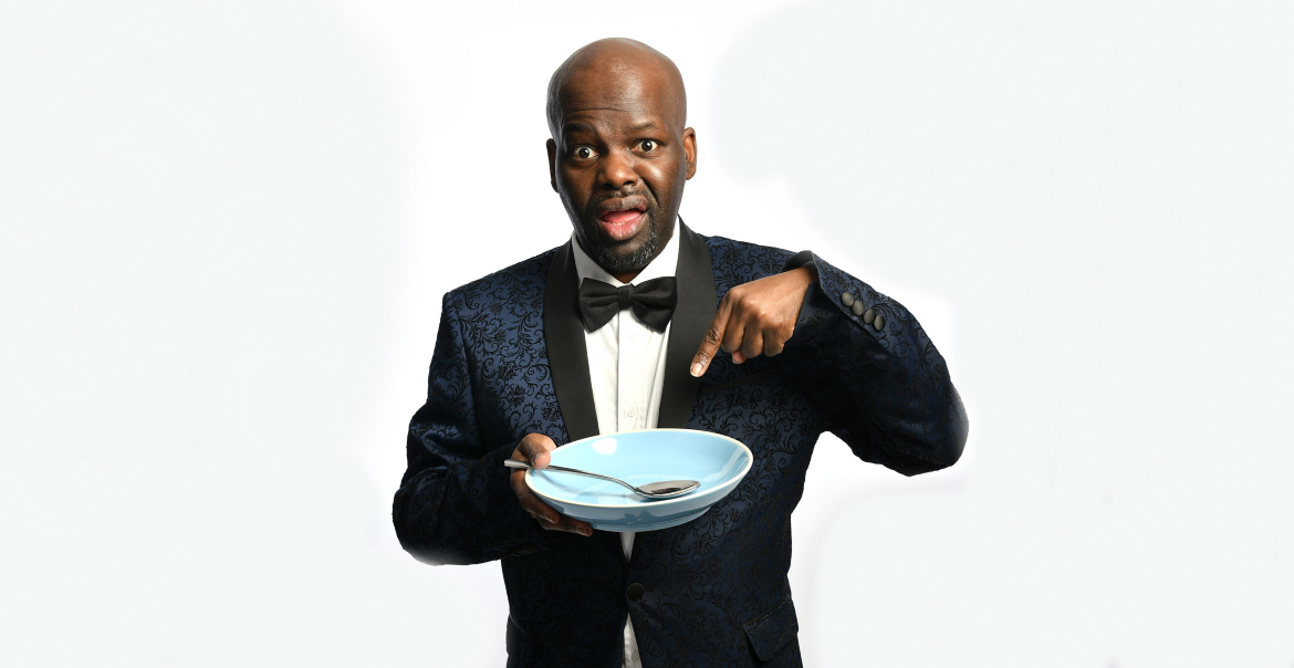 An image of a man wearing a suit, pointing to an empty bowl in his hand.