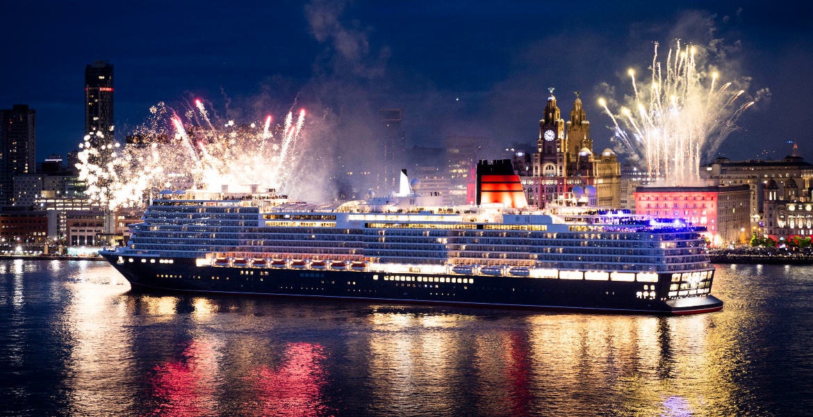 Queen Anne ship leaving Livepool at night with the iconic waterfront and fireworks in the background.