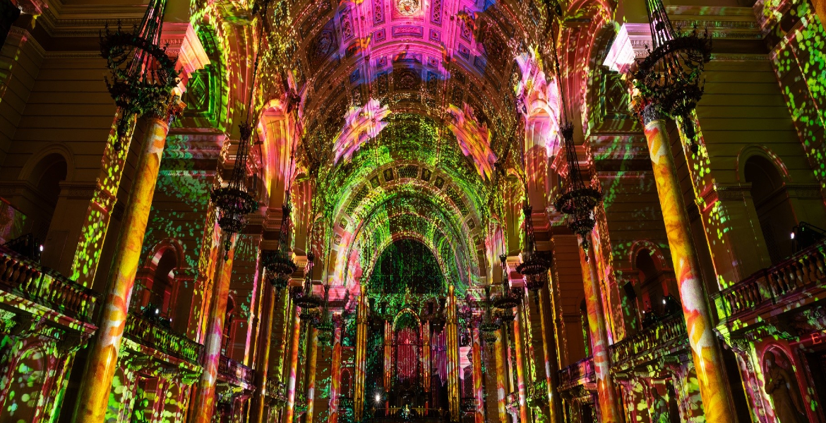 St George's Hall illuminated by vibrant lights, casting colourful patterns across the ornate ceiling.