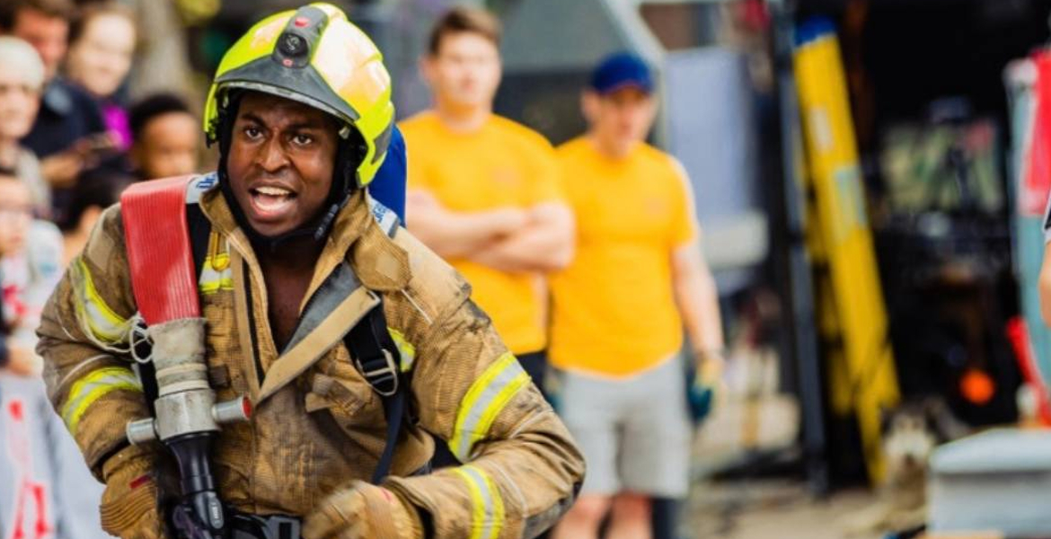 picture of a fireman dressed in his uniform equipment carrying a hose whilst taking part in the annual firefighter challenge