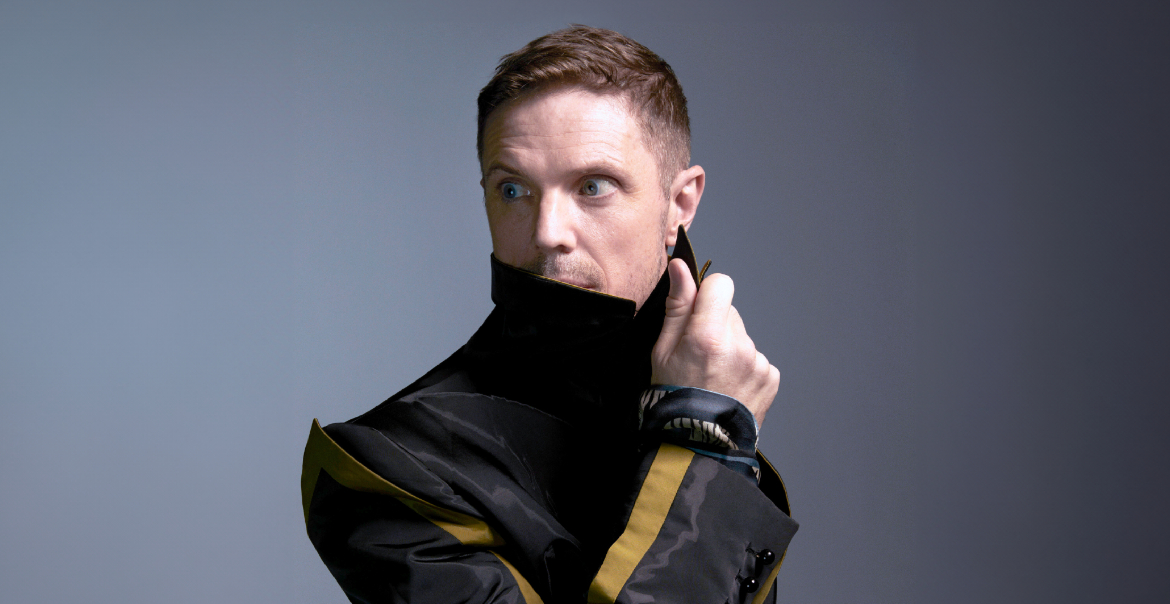 An image of Jake Shears posing with his collar over his mouth.