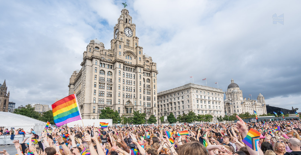 Liverpool Pier Head with Pride festival, big crowds and the Liver Bulding in the background.