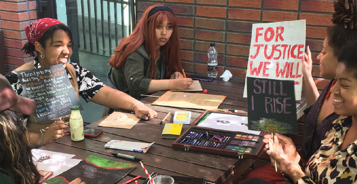 A group engaged in a sign-writing workshop around a table.