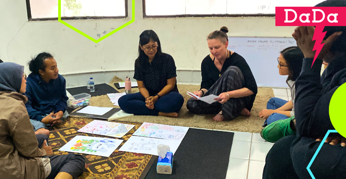 A group of people sitting on the floor during a workshop. Colorful and minimal graphics overlay the image.