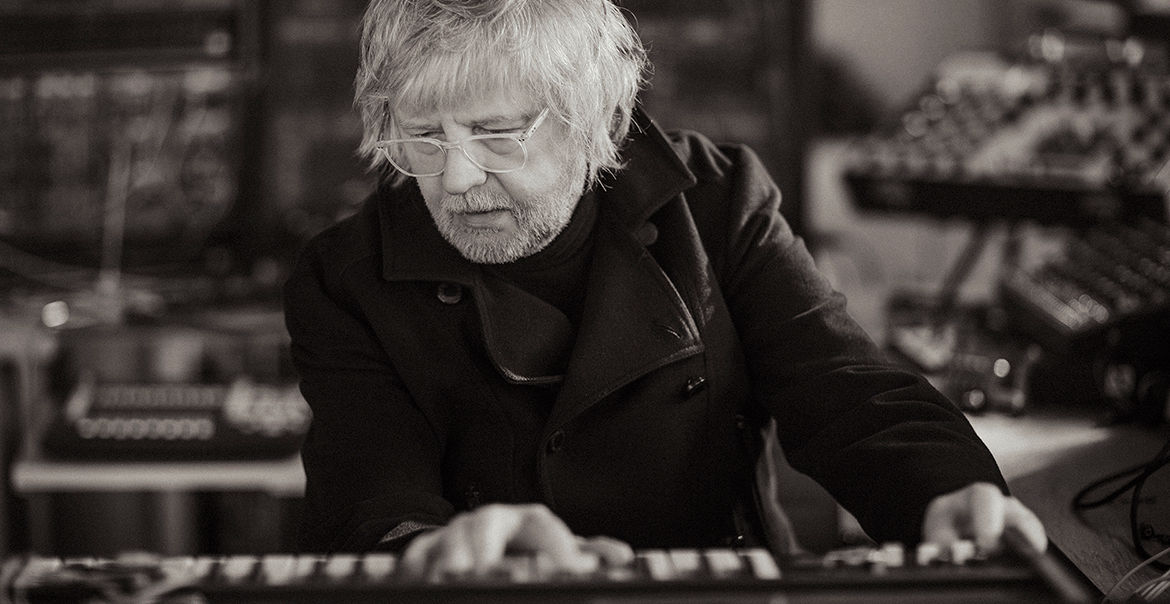 A black and white image of a man playing the synth.