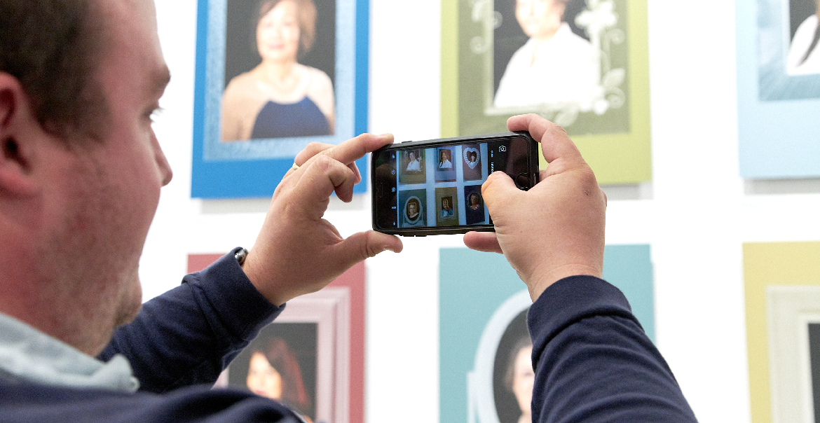 An image of a man taking a photo of an exhibition on his phone.