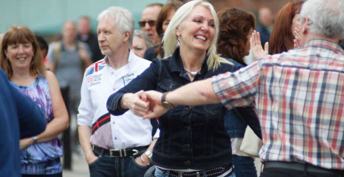 A group of people dancing outdoors at an event.