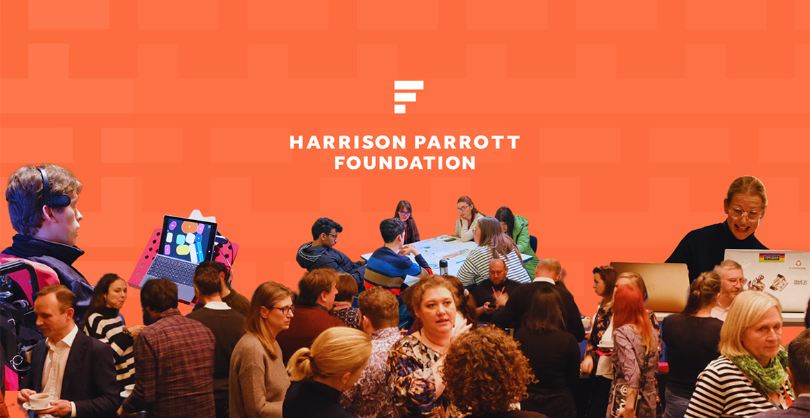 Attendees engaging in discussion at a Harrison Parrott Foundation event, set against a bright orange backdrop.